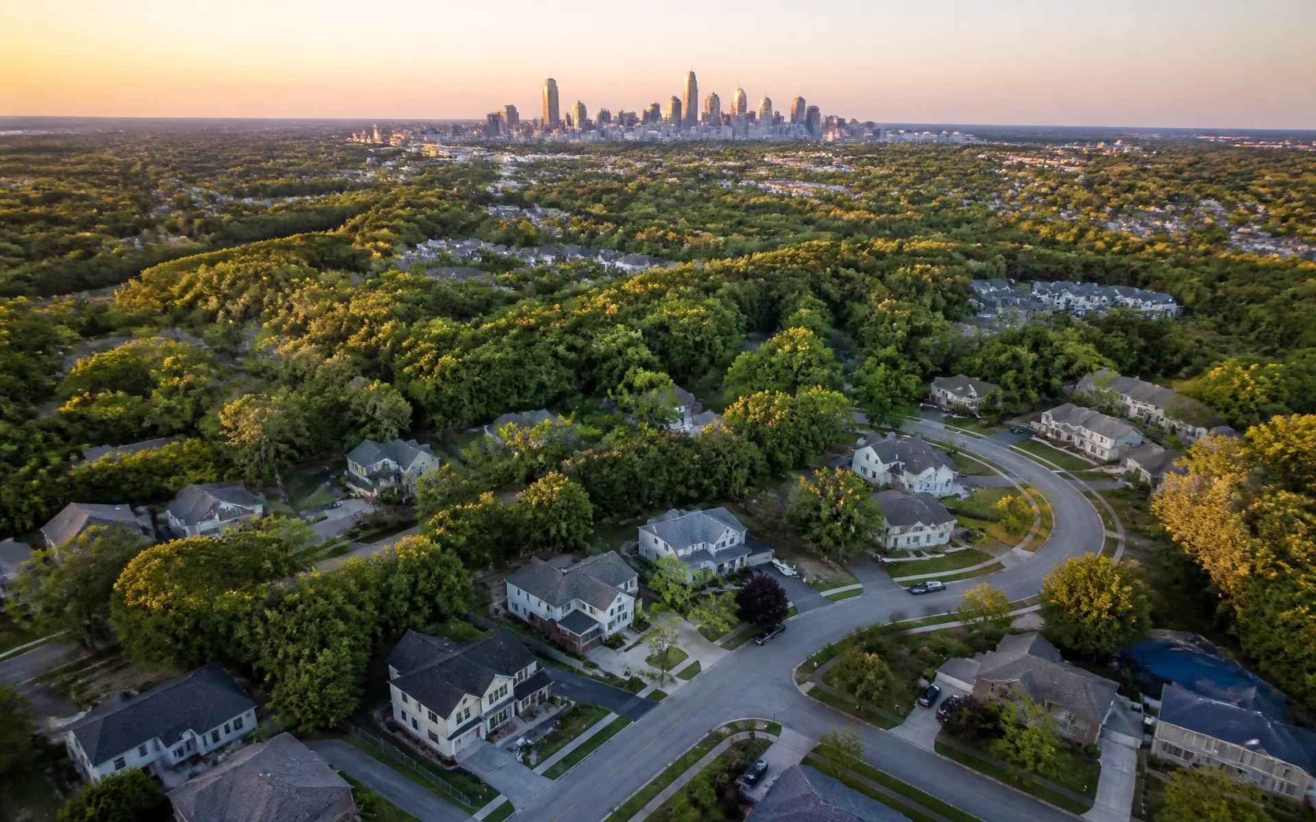 Aerial view of Charlotte's tree-canopied neighborhoods with the Uptown skyline beyond