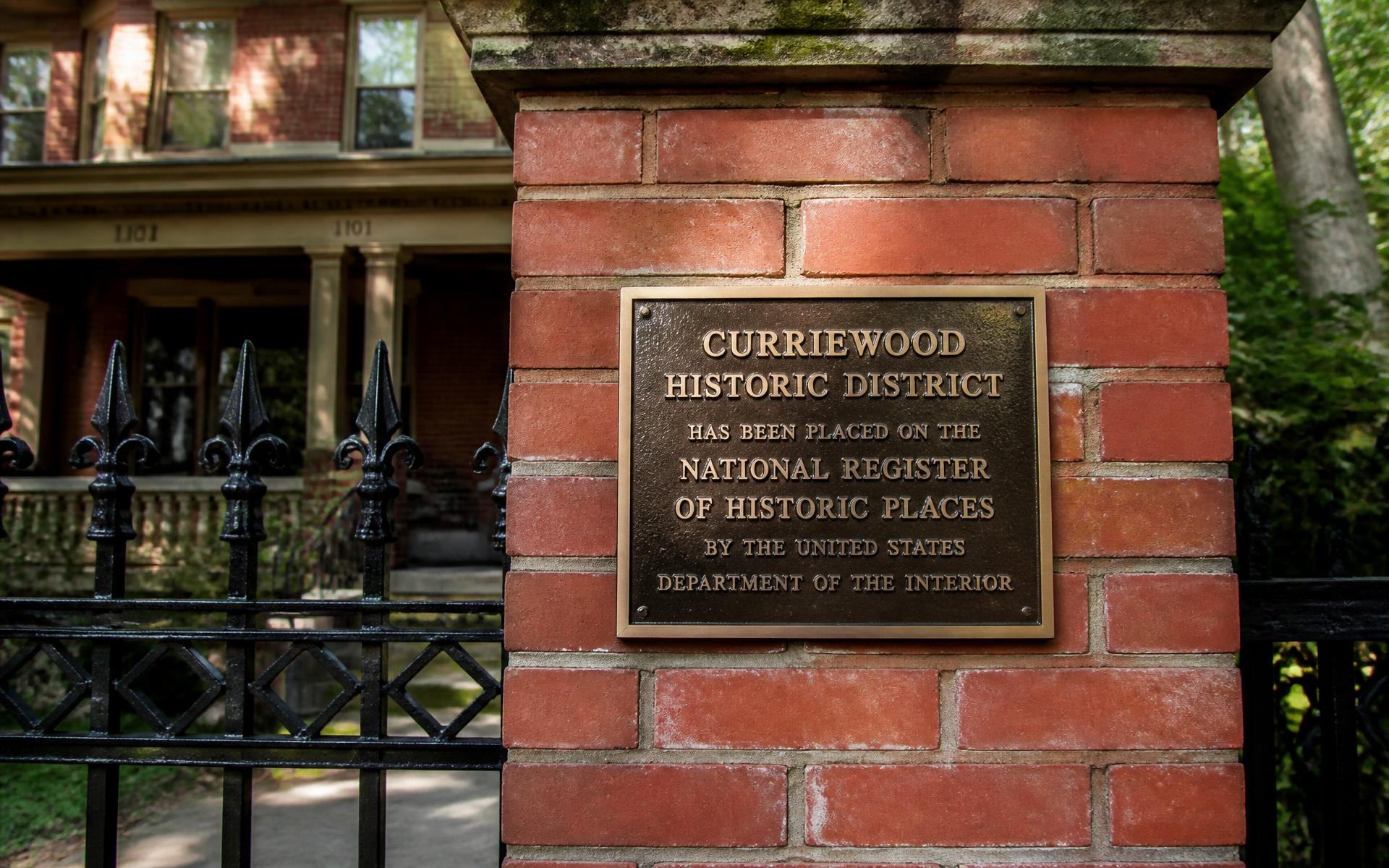 A bronze historic district plaque on a brick gatepost in Dilworth