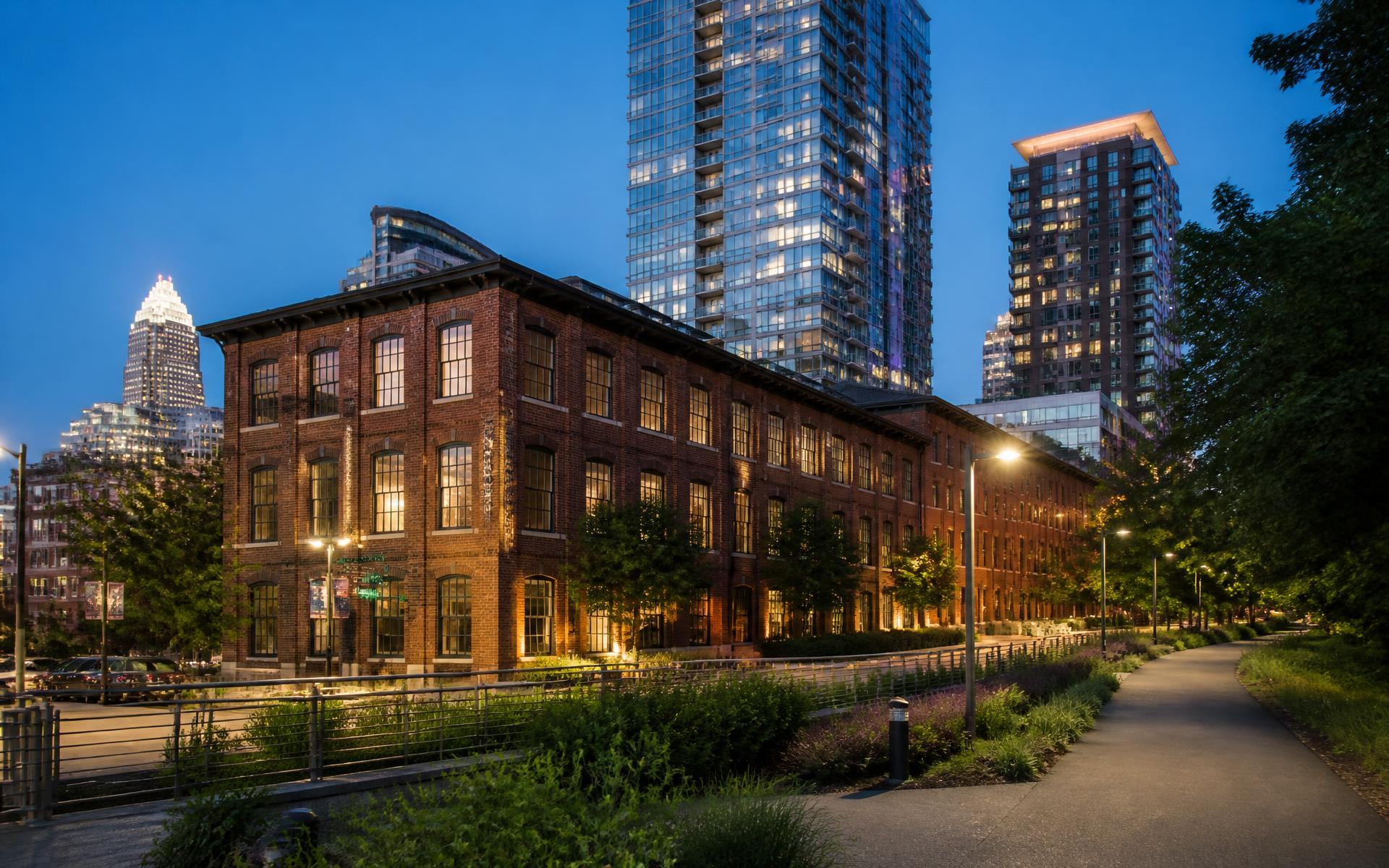 Converted brick warehouses and new towers along the Rail Trail in South End at dusk