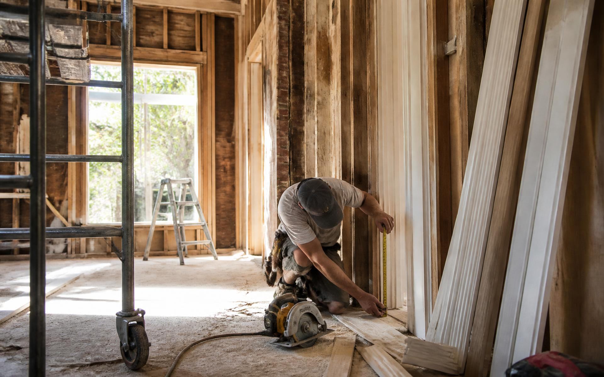 A carpenter measuring trim inside a historic Dilworth home under renovation