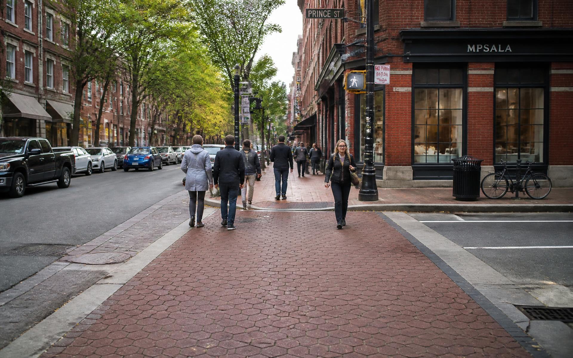 Pedestrians crossing a wide brick sidewalk on a walkable Dilworth street